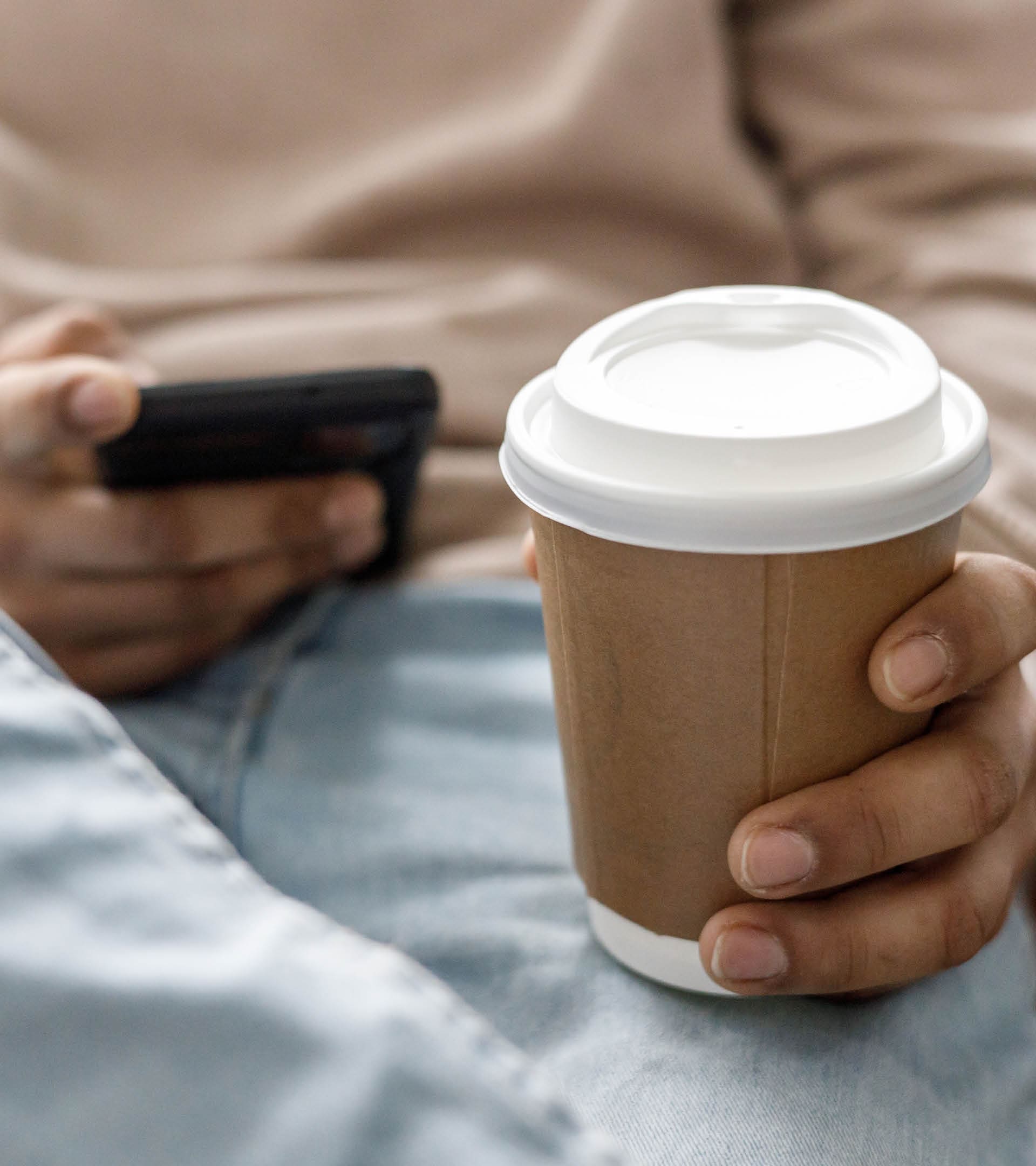 Man use of mobile phone at home while drinking in a recyclable cup