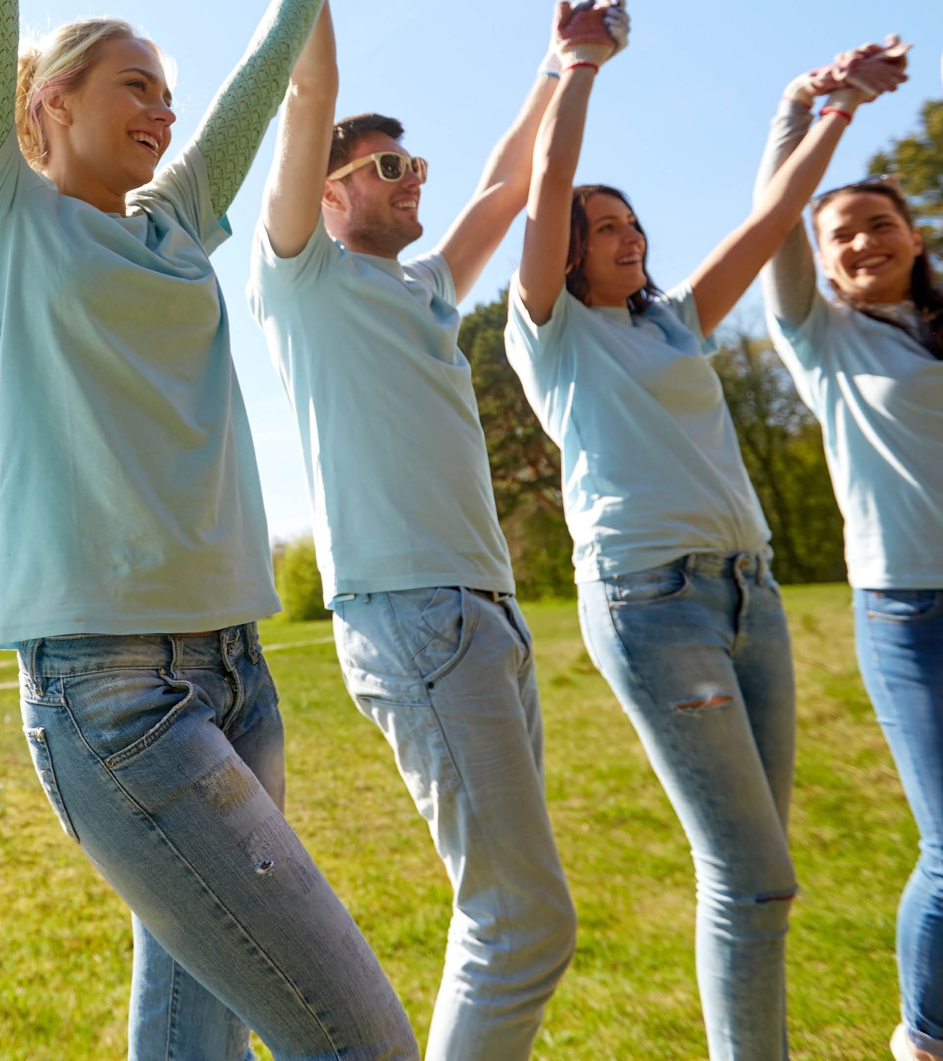 volunteering, charity and people concept - group of happy volunteers holding hands outdoors