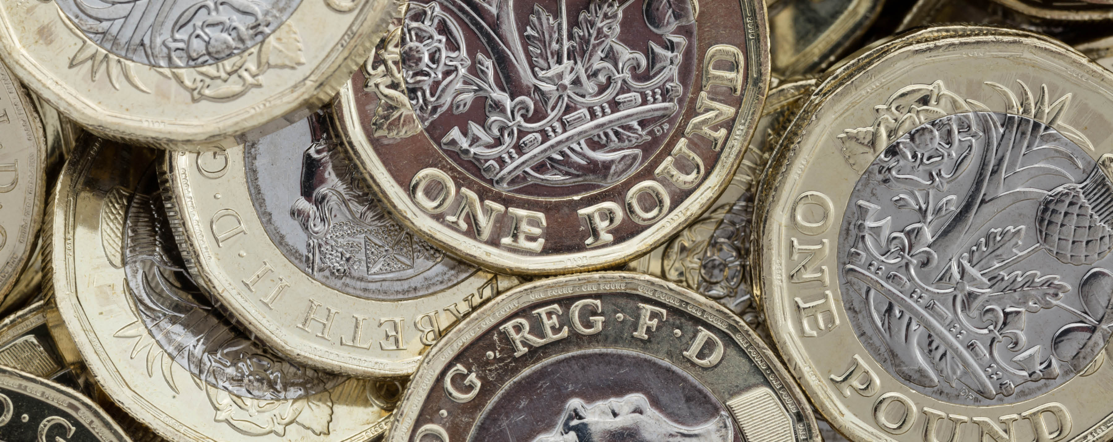 Close up of new British pound coins. Untidy pile of the new coins introduced in March 2017 that have several new security features to help prevent fraud.