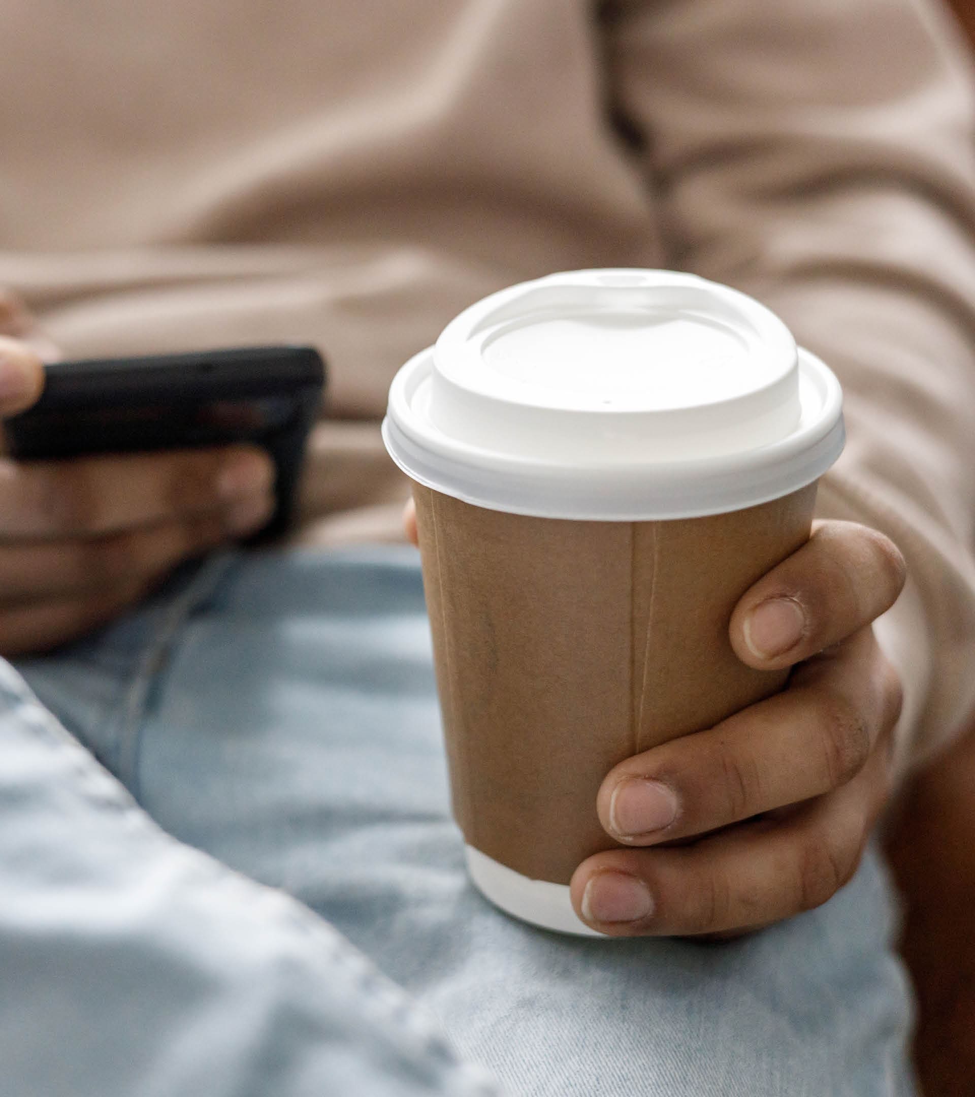 Man use of mobile phone at home while drinking in a recyclable cup
